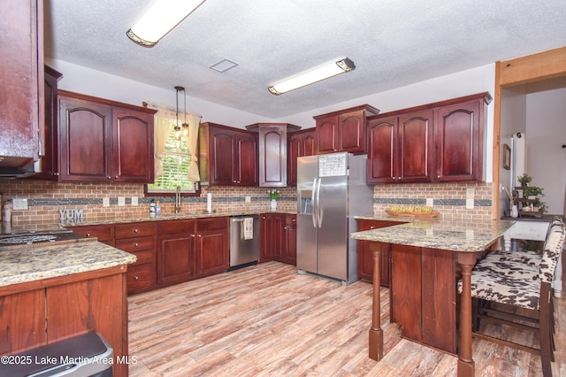 93 Restful Cv, Dadeville, AL 36853 - kitchen featuring appliances with stainless steel finishes, a peninsula, tasteful backsplash, light wood-style floors, and a textured ceiling