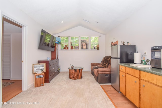 93 Restful Cv, Dadeville, AL 36853 - kitchen with freestanding refrigerator, lofted ceiling, dark countertops, light wood-type flooring, and light carpet