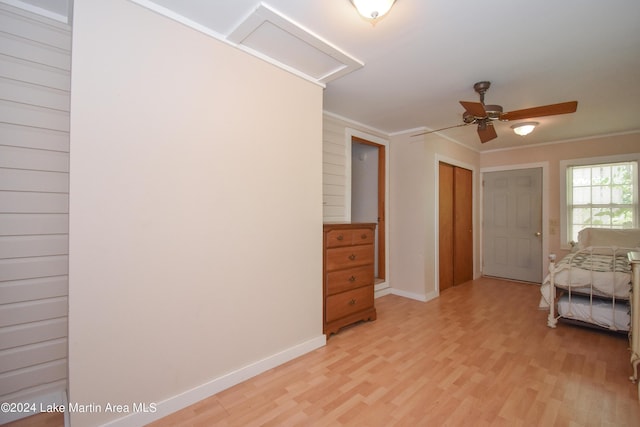 unfurnished bedroom with ceiling fan, a closet, ornamental molding, and light hardwood / wood-style flooring