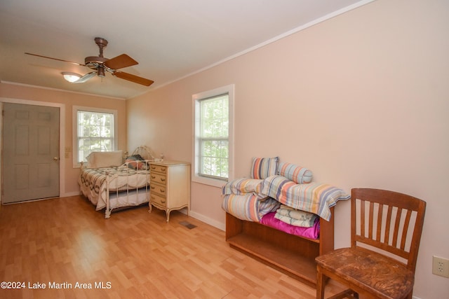 bedroom featuring multiple windows, ceiling fan, crown molding, and light wood-type flooring