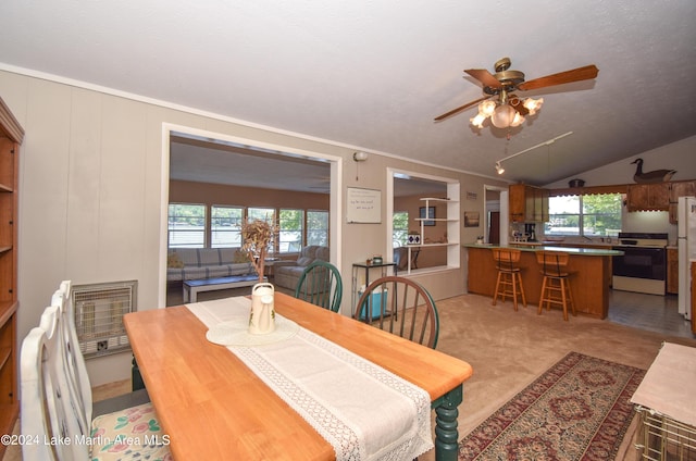 dining area featuring light carpet, lofted ceiling, ceiling fan, and a healthy amount of sunlight