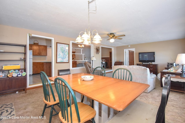 dining area featuring a textured ceiling and ceiling fan with notable chandelier