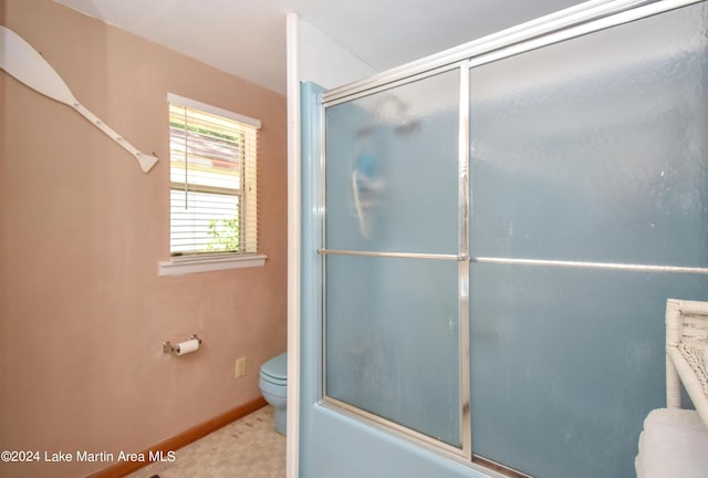 bathroom featuring toilet and bath / shower combo with glass door