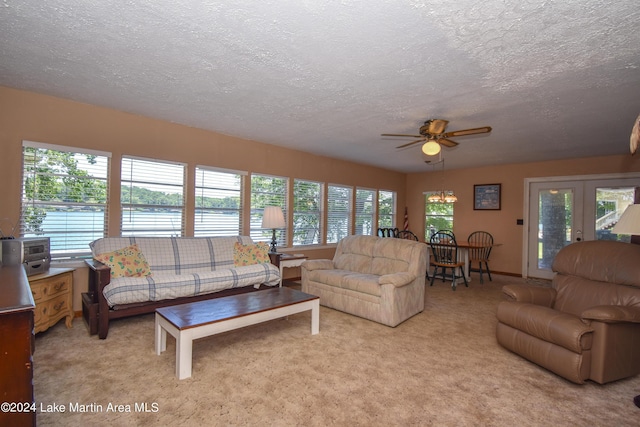 carpeted living room featuring ceiling fan, a healthy amount of sunlight, and a water view