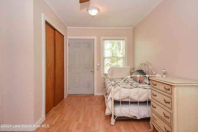 bedroom with light wood-type flooring, a closet, ornamental molding, and ceiling fan