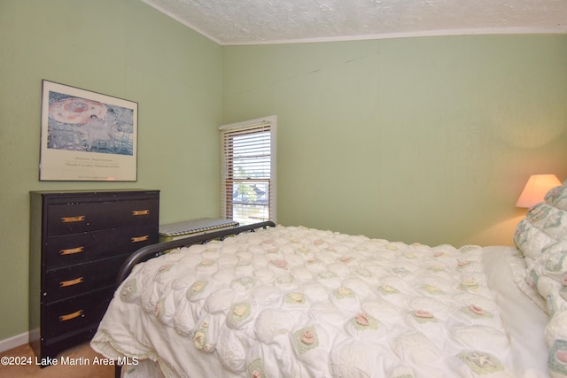 bedroom with a textured ceiling, lofted ceiling, and ornamental molding