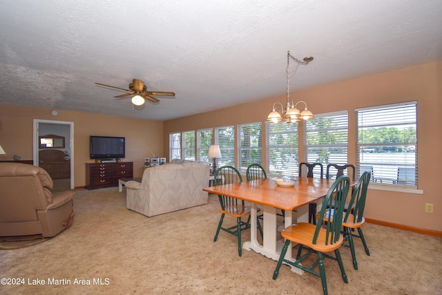 carpeted dining space with a textured ceiling and ceiling fan with notable chandelier