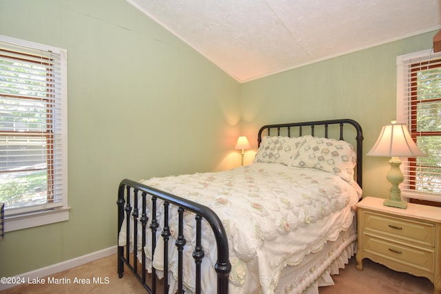 bedroom with a textured ceiling, light colored carpet, and lofted ceiling