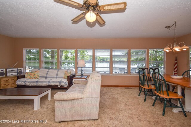 carpeted living room with plenty of natural light, a textured ceiling, and ceiling fan with notable chandelier