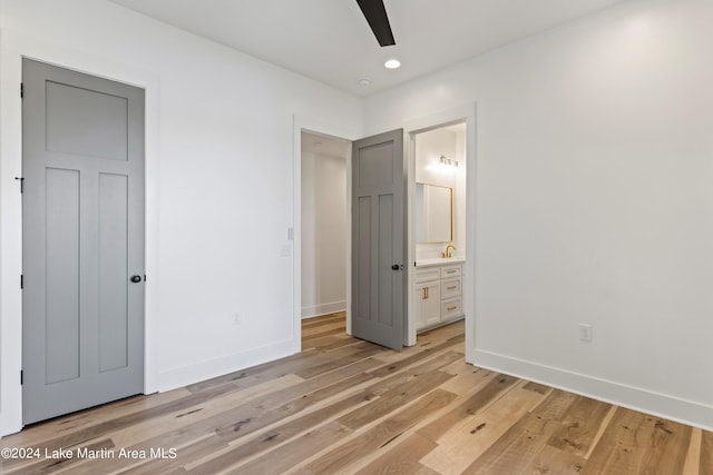 unfurnished bedroom featuring ensuite bath, ceiling fan, sink, and light wood-type flooring