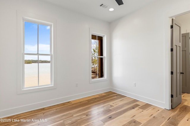 unfurnished room featuring visible vents, light wood-style flooring, a ceiling fan, and baseboards