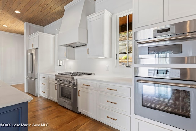 kitchen featuring high end appliances, light countertops, custom range hood, white cabinets, and wood ceiling