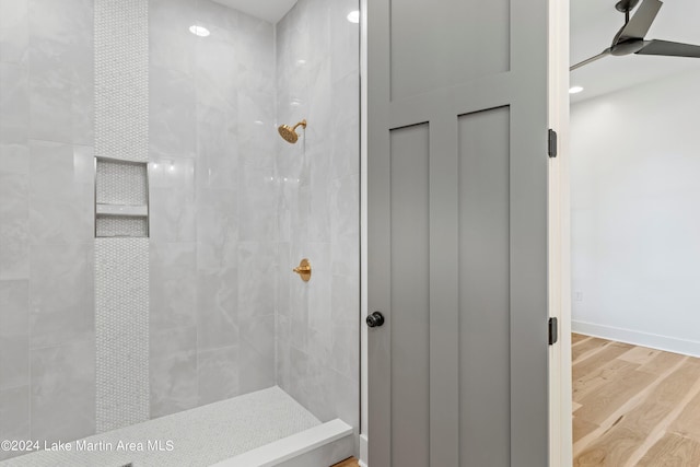 bathroom with ceiling fan, wood-type flooring, and tiled shower