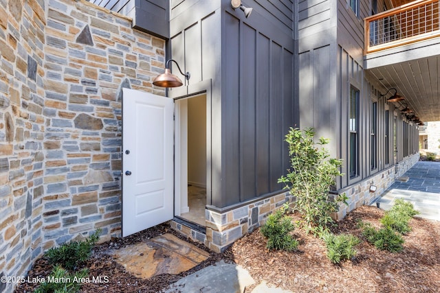 doorway to property with board and batten siding and stone siding