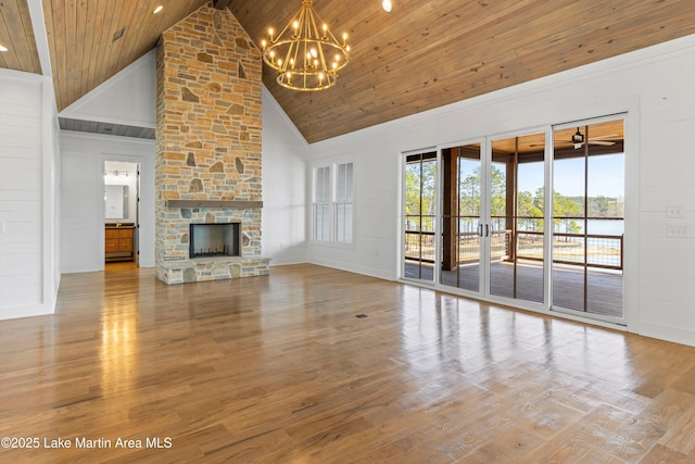 unfurnished living room with wood finished floors, high vaulted ceiling, a stone fireplace, wood ceiling, and ceiling fan with notable chandelier