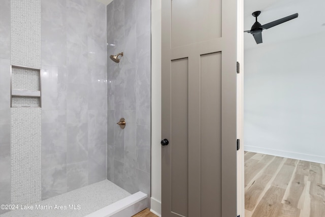 bathroom with tiled shower, hardwood / wood-style floors, and ceiling fan