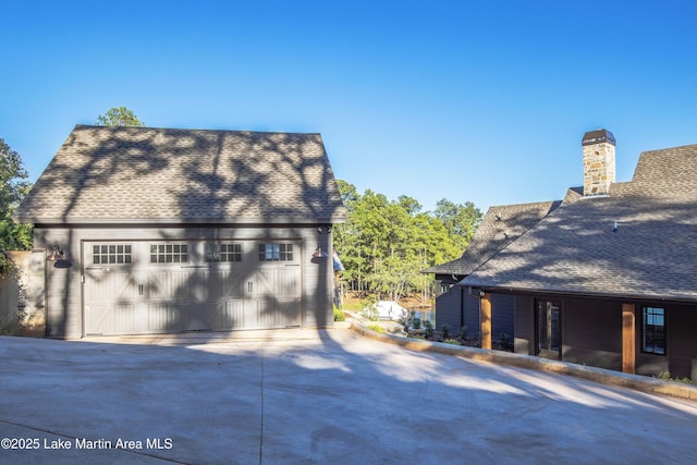 view of property exterior featuring a garage and a shingled roof