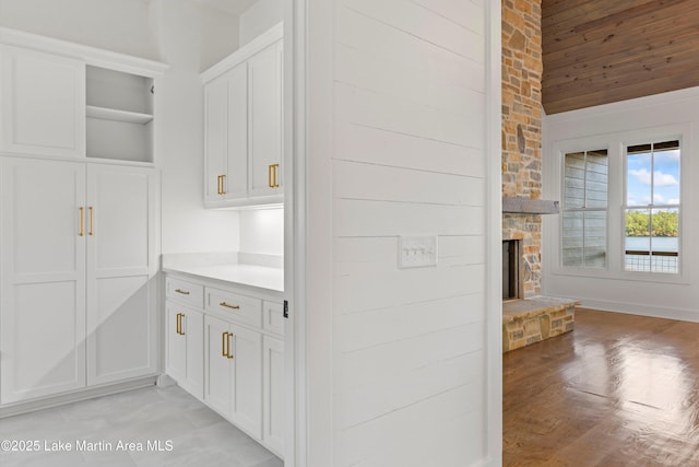 bar with a stone fireplace, lofted ceiling, and light wood-type flooring