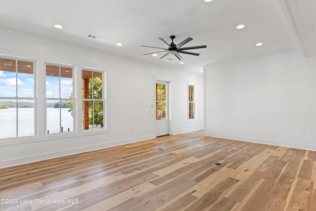 empty room featuring a wealth of natural light, a water view, and light hardwood / wood-style floors