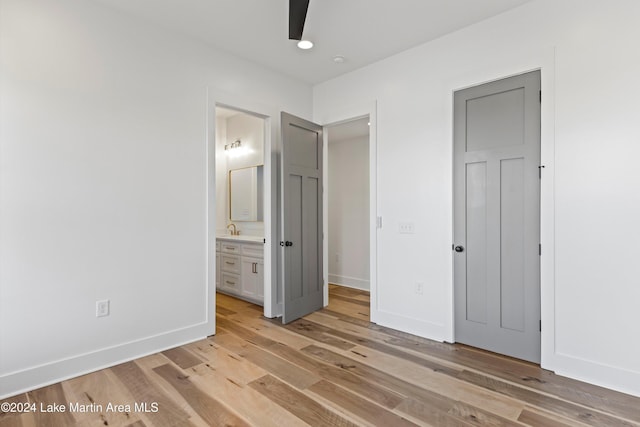 unfurnished bedroom featuring ensuite bathroom, light hardwood / wood-style flooring, ceiling fan, and sink