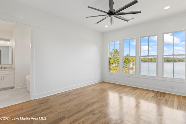 spare room featuring a water view, light hardwood / wood-style flooring, and ceiling fan