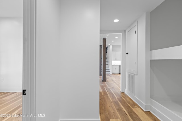 hallway featuring visible vents, recessed lighting, baseboards, and wood finished floors