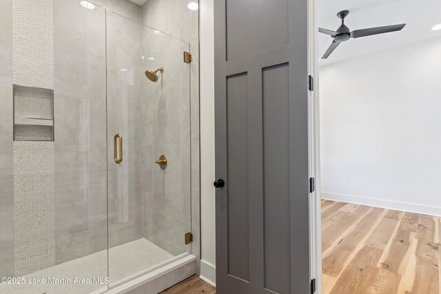 bathroom featuring baseboards, wood finished floors, a stall shower, and ceiling fan