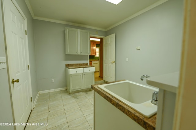 kitchen with sink, white cabinetry, ornamental molding, and light tile patterned floors