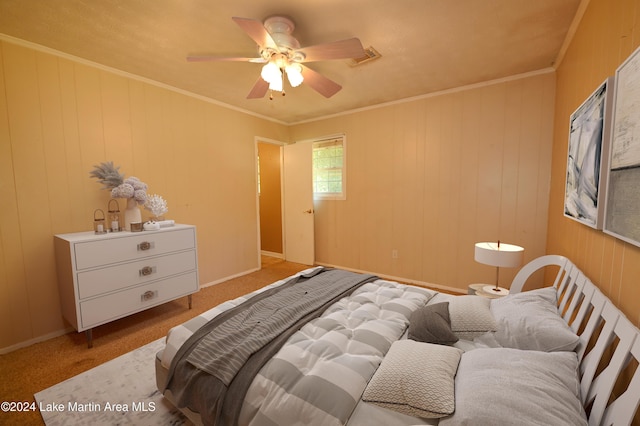 carpeted bedroom featuring wooden walls, ceiling fan, and ornamental molding