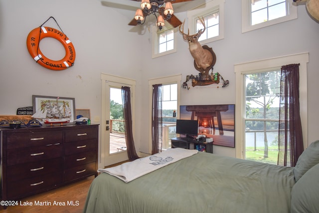 bedroom with access to exterior, a high ceiling, light hardwood / wood-style floors, and ceiling fan