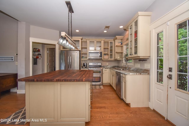 kitchen with butcher block countertops, pendant lighting, a kitchen island, and stainless steel appliances