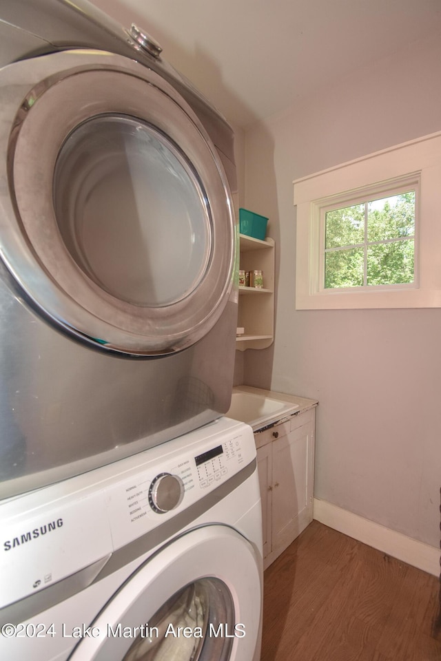 washroom with dark hardwood / wood-style floors, cabinets, and stacked washing maching and dryer