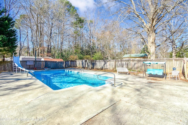 view of swimming pool with a patio area and a water slide