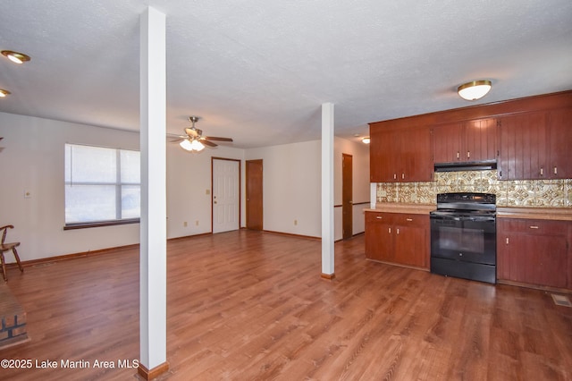 kitchen featuring ceiling fan, black electric range oven, ventilation hood, wood-type flooring, and decorative backsplash