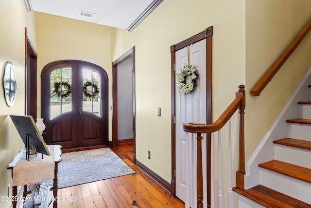 foyer entrance featuring arched walkways, visible vents, baseboards, french doors, and wood-type flooring