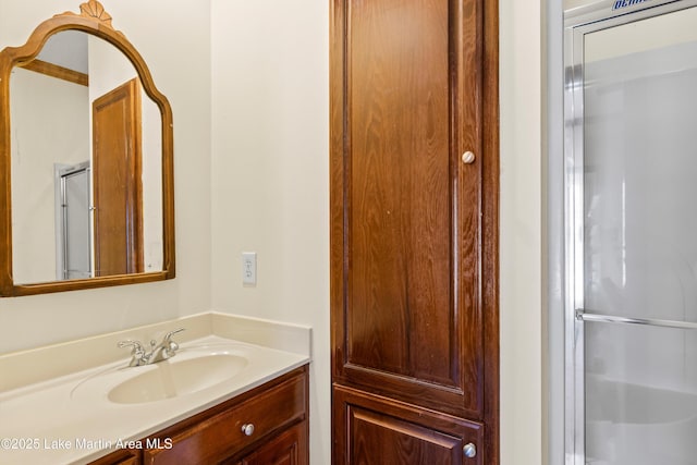 full bath featuring a shower with shower door and vanity