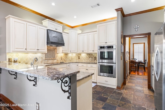 kitchen featuring stainless steel appliances, a peninsula, a kitchen breakfast bar, ornamental molding, and ventilation hood