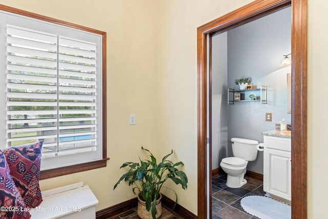 bathroom featuring toilet, vanity, and baseboards