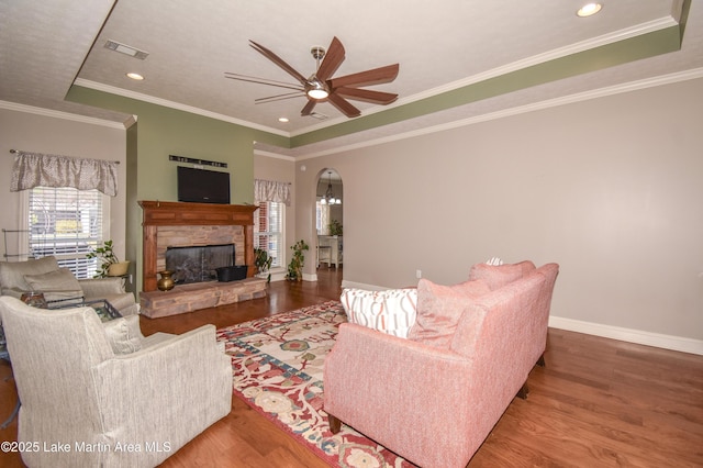 living room with a ceiling fan, visible vents, wood finished floors, baseboards, and arched walkways