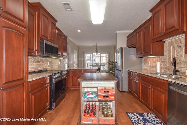 kitchen featuring light wood-type flooring, visible vents, a sink, stainless steel appliances, and crown molding