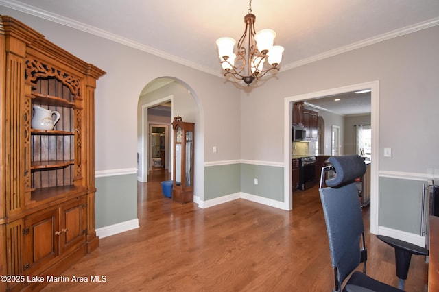 interior space with baseboards, ornamental molding, an inviting chandelier, wood finished floors, and arched walkways