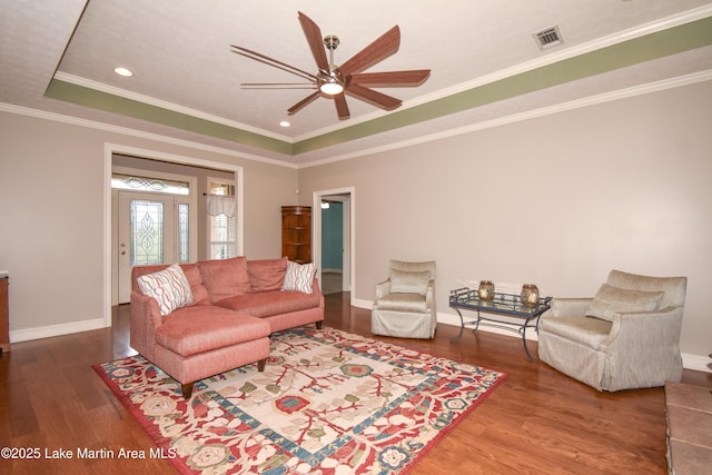 living room with a raised ceiling, wood finished floors, visible vents, and baseboards