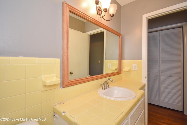 bathroom featuring wood-type flooring, vanity, and tile walls