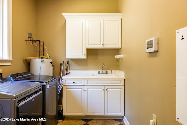 clothes washing area featuring water heater, cabinets, sink, and washing machine and clothes dryer