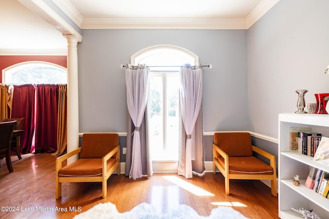 sitting room with hardwood / wood-style flooring, ornate columns, and ornamental molding