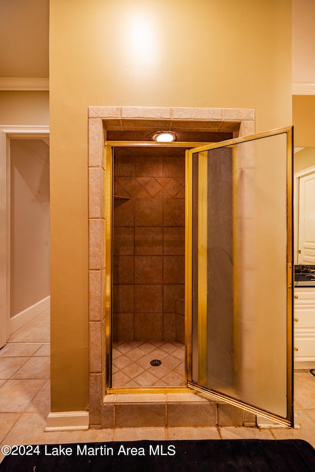 bathroom featuring tile patterned flooring, a shower with door, and ornamental molding