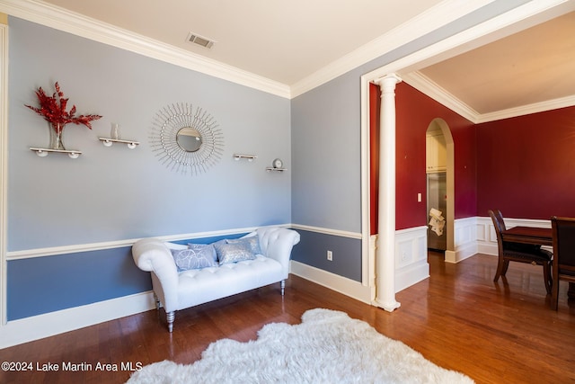 living area featuring wood-type flooring, ornamental molding, and ornate columns