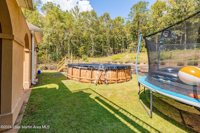 view of yard featuring a trampoline and a covered pool