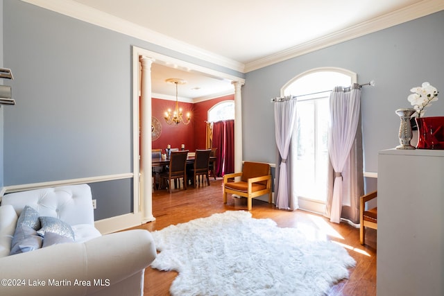 living room featuring light hardwood / wood-style flooring, ornate columns, crown molding, and a notable chandelier