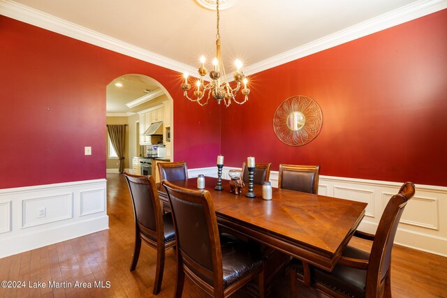 dining room featuring crown molding, wood-type flooring, and an inviting chandelier